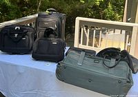 Four travel bags displayed on table outdoors