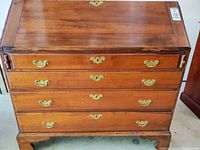 Front view showing drawers, brass hardware, bracket feet