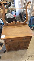 Full front view of oak washstand showing towel bar, drawer, doors, casters