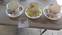 Three bone china teacup and saucer sets on table