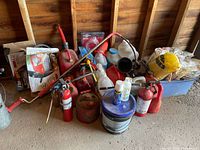 overall view of fuel cans, extinguishers, siphons, chemicals piled against wall