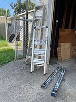 Vulcan ladder, Step-N-Store stool, and two folding ramps leaning against garage