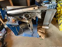 Table saw on side showing blue cabinet, motor, switch and accessories stacked