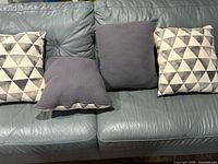 All four pillows on sofa: two geometric pattern, two solid gray