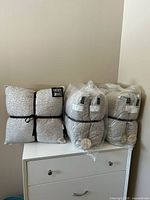 Three factory bundles of two pillows each on dresser