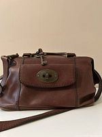 Front view showing leather, turn-lock pocket, handles, strap