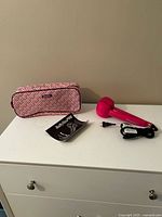 Hair curler, travel case and manual on dresser