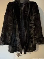Full front view of black mink coat on hanger