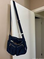 Full view of navy crossbody purse hanging to show overall design and strap length