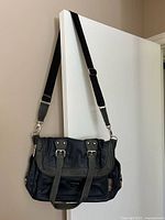 Front view showing two-tone design, flap, buckles, crossbody strap attached