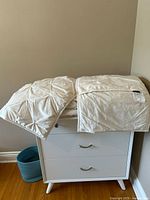 Folded ivory comforter with diamond pintuck pattern on dresser