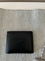 Front view of closed black leather wallet on fabric background