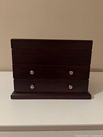 Front view showing dark wood exterior and drawer knobs