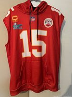 Front of red sleeveless hooded vest showing number 15, patches, pocket