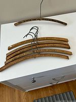 Six wooden hangers on white surface showing branding