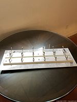 Package showing two white wood racks with brushed nickel hooks