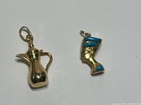 Both gold charms side by side on white background