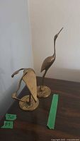 Both brass heron statues on table with measurement labels