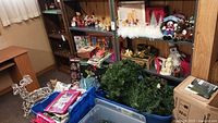 Overall view of shelving with assorted Christmas items, wire sleigh, storage totes and boxed trees