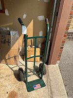 Front view of green metal hand truck showing full frame and wheels