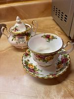 Tea cup on saucer with covered sugar bowl, showing pattern and gold trim