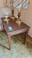 Side table with brass lamps on top, showing overall design and finish
