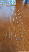 Four sterling silver necklaces laid flat showing chain styles and pendant