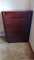 Front view of dark wood five-drawer dresser
