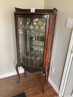 Full view of curio cabinet showing bowed leaded glass door, wood frame, cabriole legs