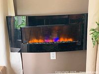 Front view of curved black wall-mount electric fireplace with flame effect