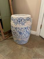 Full view of blue and white ceramic garden seat showing shape, pattern and condition