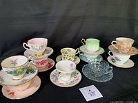 Front view of 11 teacup and saucer sets on black background