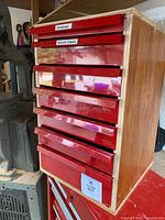 Front view of cabinet showing seven red drawers and labels