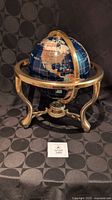 Gemstone inlaid globe on brass stand showing meridian ring, compass in base, overall appearance