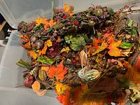 Large clear tote filled with artificial fall garlands, leaves, berries and pumpkins