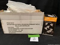 Closed carton labeled LED Purple Orange 120L Starburst with 2 Way Flash Controller alongside Whirl-a-Motion projection light box