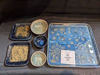 All six pottery pieces arranged: large floral tray, two square plates, three round bowls