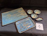 All seven pottery pieces laid out, showing glaze and motif