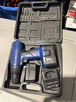 Open carry case showing drill, battery, charger, adapter, drill bits and driver bits
