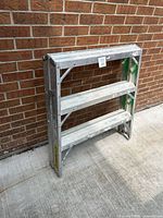 Ladder folded against wall showing overall size and three step rungs