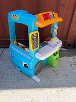 Front exterior of Fisher-Price food truck playset showing headlights, wheels, service window and menu board