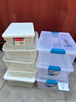 Stack of Rubbermaid and Sterilite clear plastic bins showing quantity and overall condition