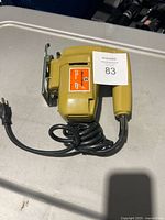 Left side view of yellow Black & Decker jig saw with coiled cord and MaxSold tag 83