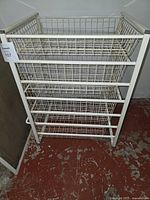 Front view of steel storage cart showing four removable wire baskets and frame