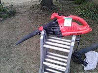 Red Black & Decker leaf blower on ladder, nozzle visible