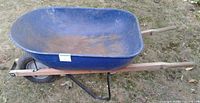 Side view of blue wheelbarrow showing tub, handles, single wheel