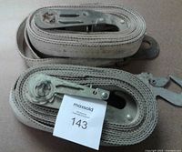Pair of rolled ratchet tie-down straps showing metal mechanisms and hooks