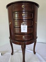Front view of cherry wood standing jewellery armoire showing drawers and legs