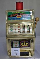 Front view shows gold-tone Casino Crown slot machine bank with reels, payout tray, and red top light