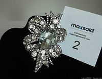 Front view of brooch showing blue crystal center and surrounding clear rhinestones